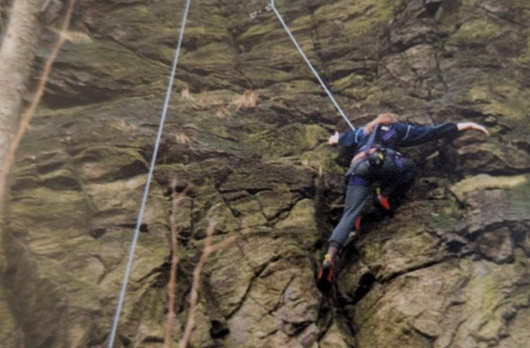 Ein etwa elfjähriges Mädchen klettert konzentriert an einem Felsen aus rotem Sandstein in der Pfalz. Das Bild symbolisiert Freiheit, Kindheit und die Leidenschaft fürs Klettern.