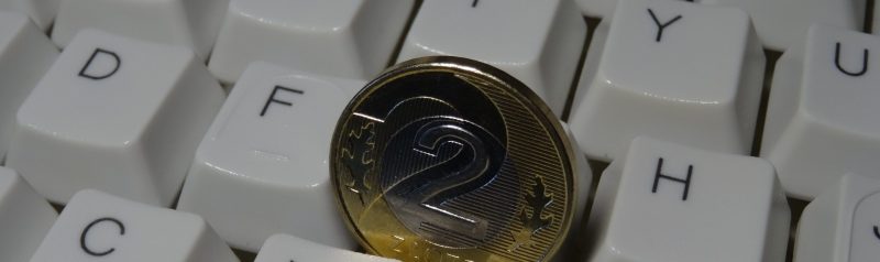 Zwei Euro Münze zwischen Tastaturtasten als Symbol für Preise und Leistungen im Copywriting